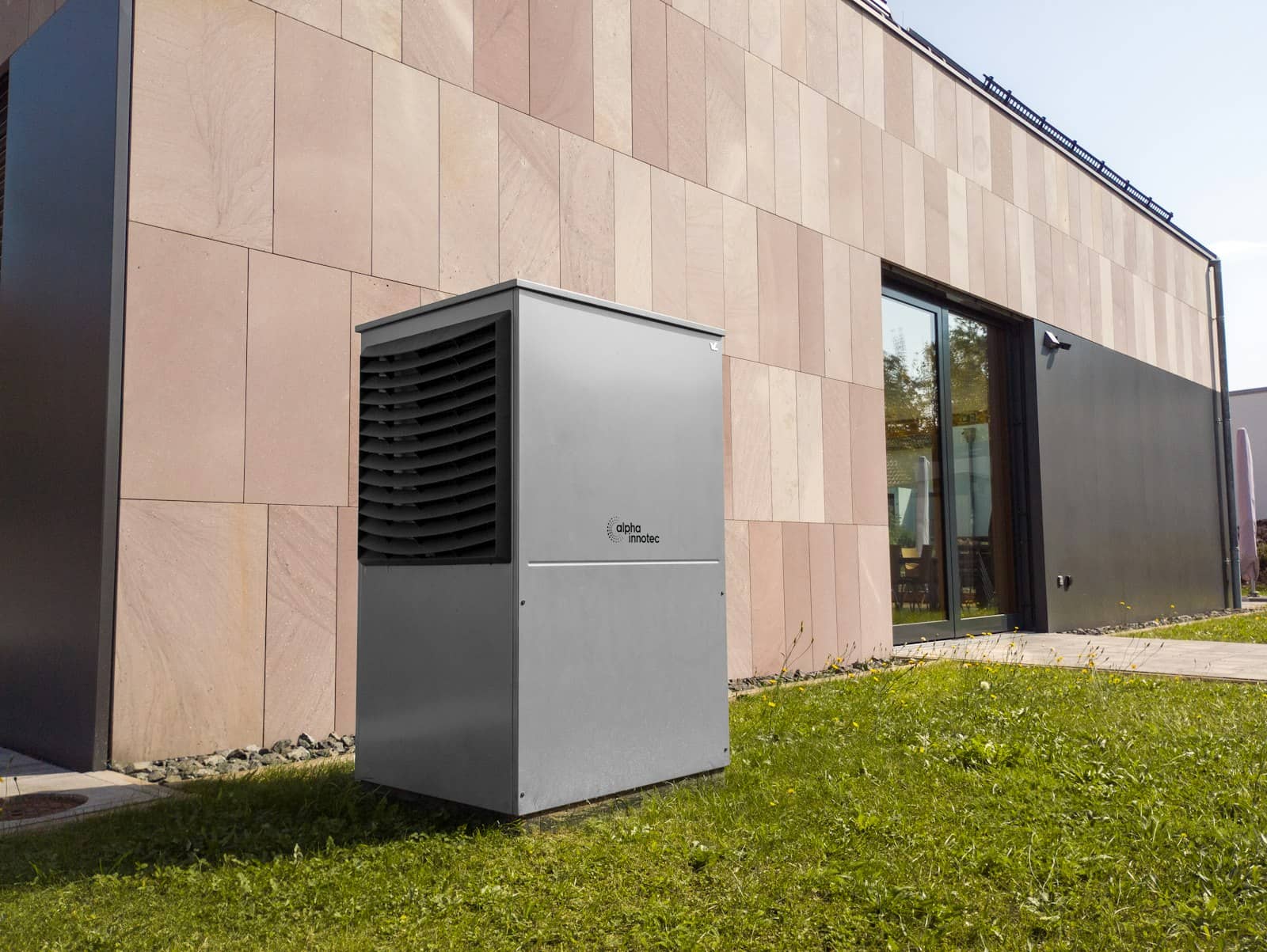 Warmtepomp buitenunit op het gras naast een moderne woning